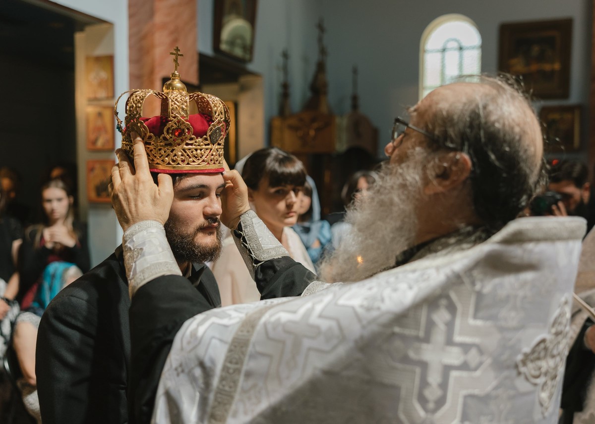 A priest places the wedding crown on the groom