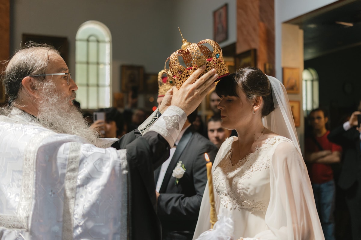 An Orthodox priest holds an ornate wedding crown above the bride