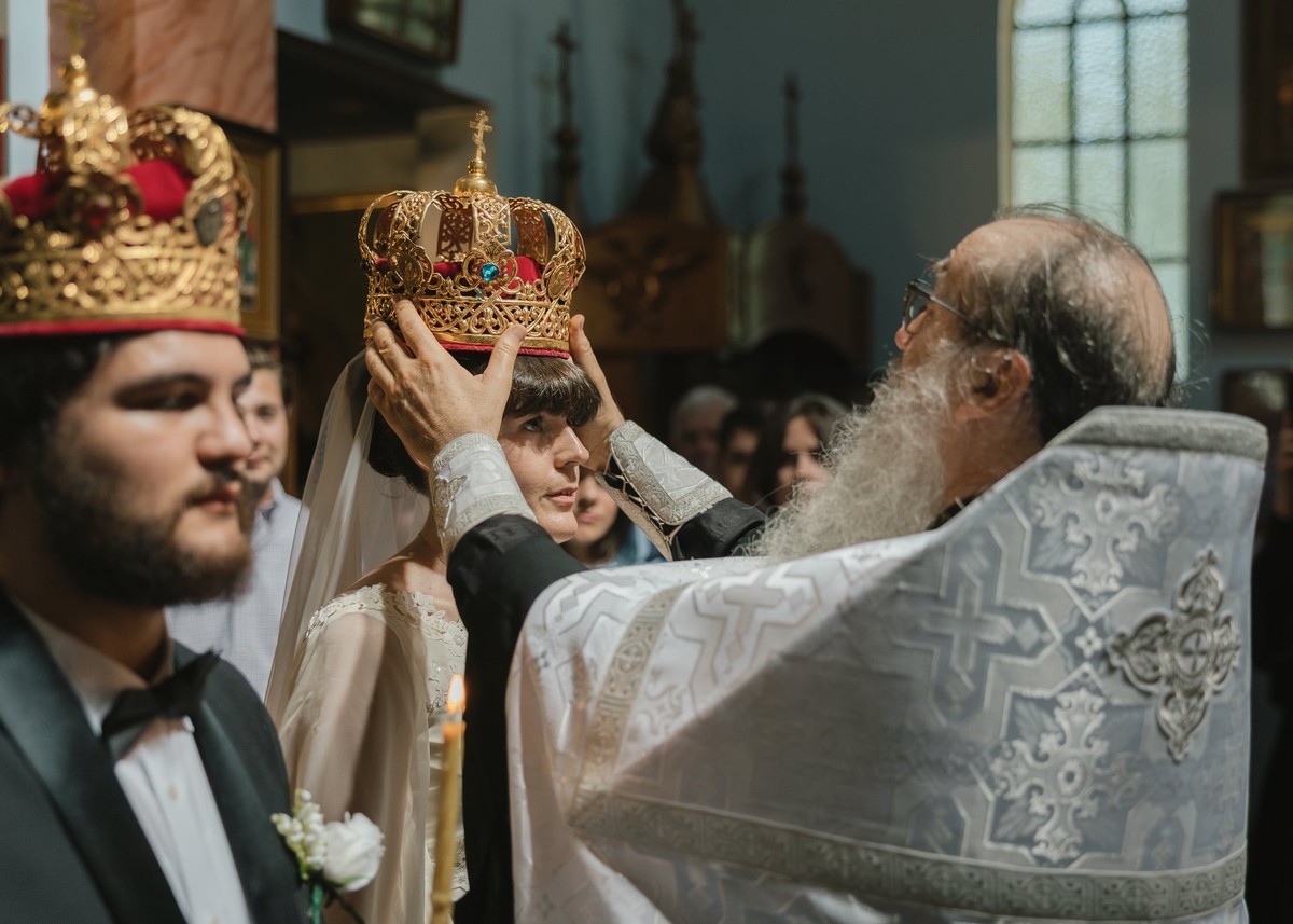An Orthodox priest holds an ornate wedding crown above the bride