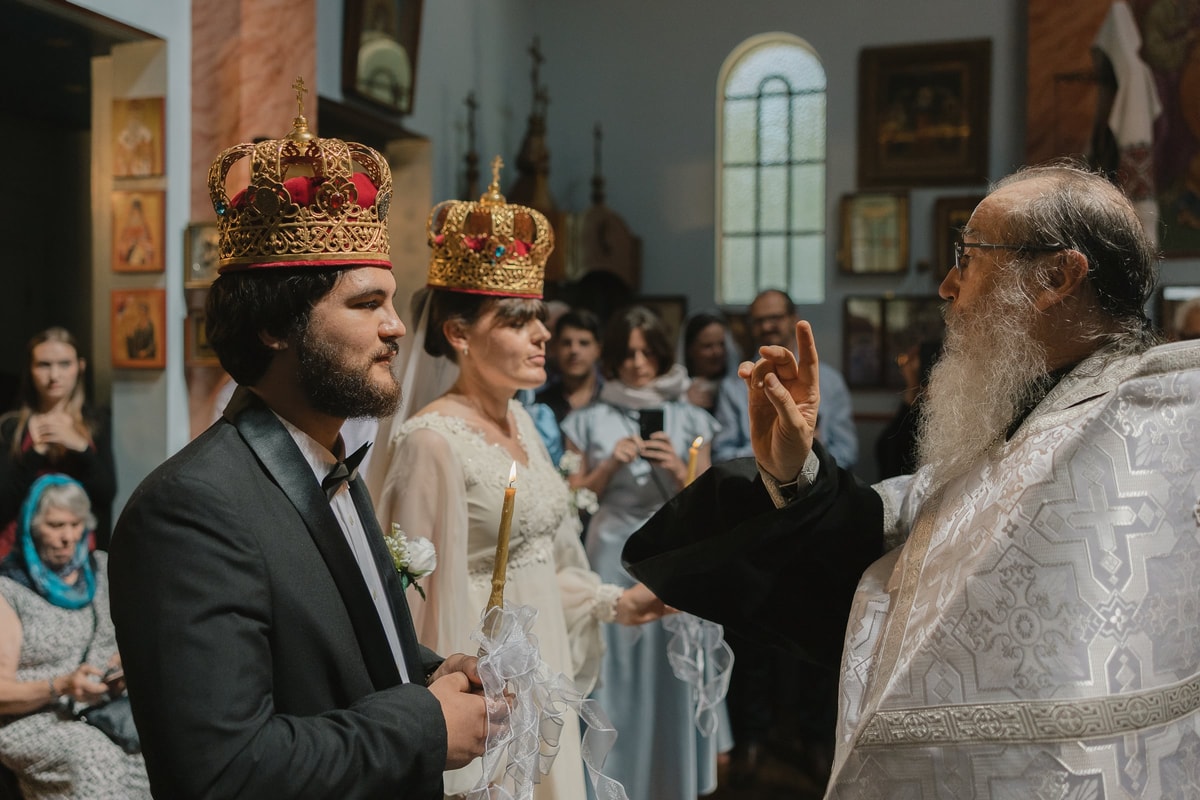 The groom wears his crown as the bishop gives a blessing