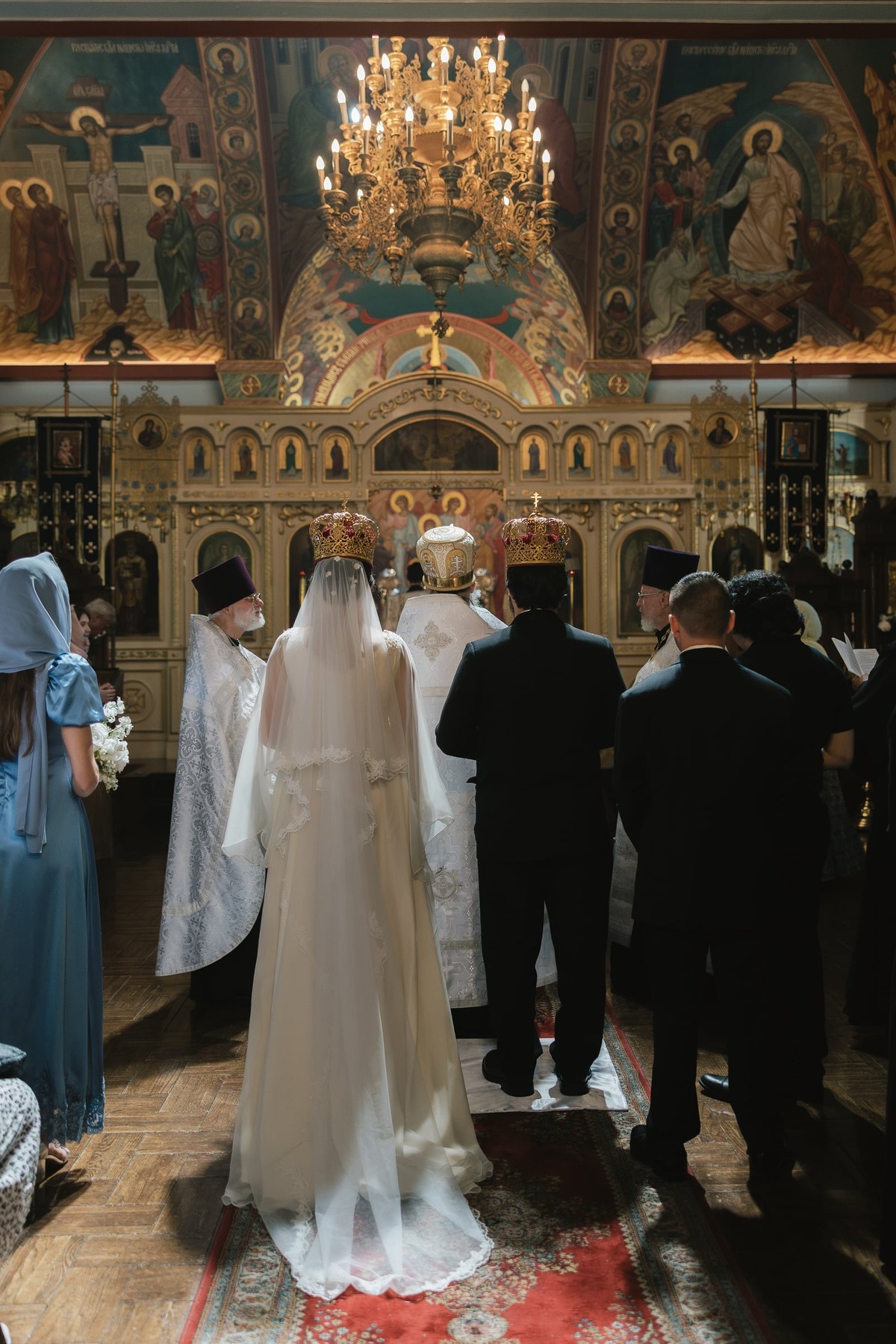 The bride and groom stand crowned before the iconostasis