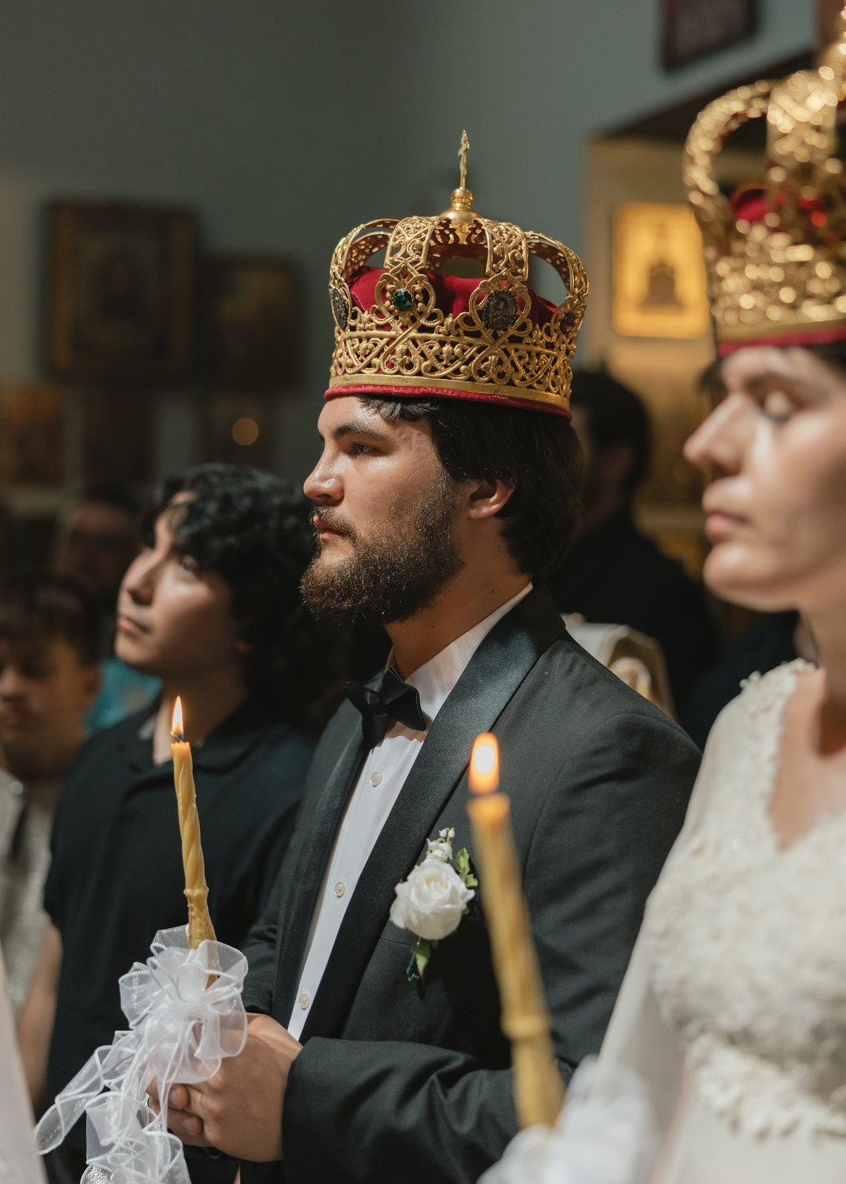 The crowned couple holds candles during the marriage service