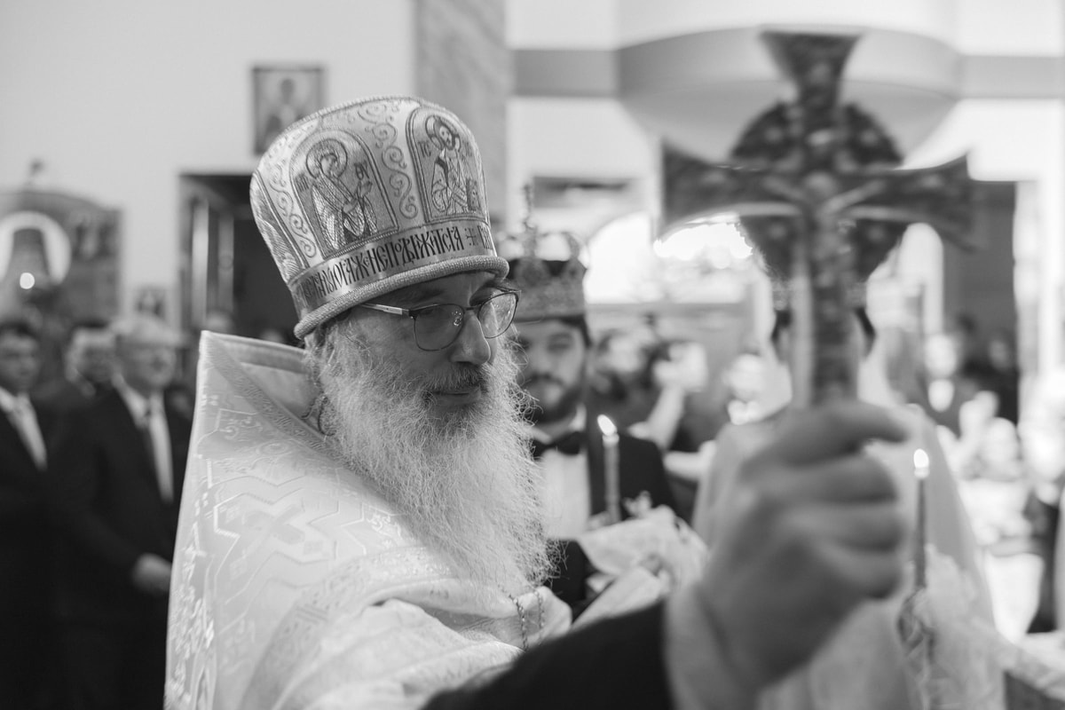 A bishop holds a lighted candle in a black-and-white photograph