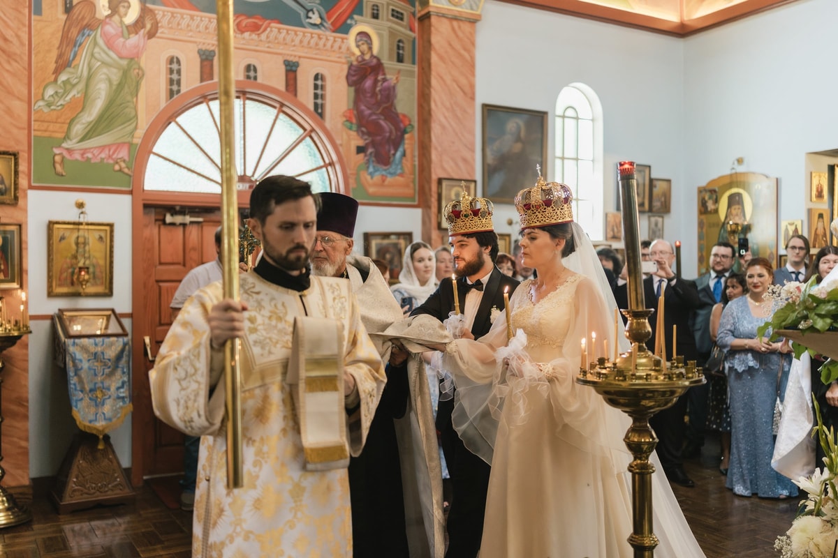 An Orthodox priest leads a crowned bride and groom in the wedding procession