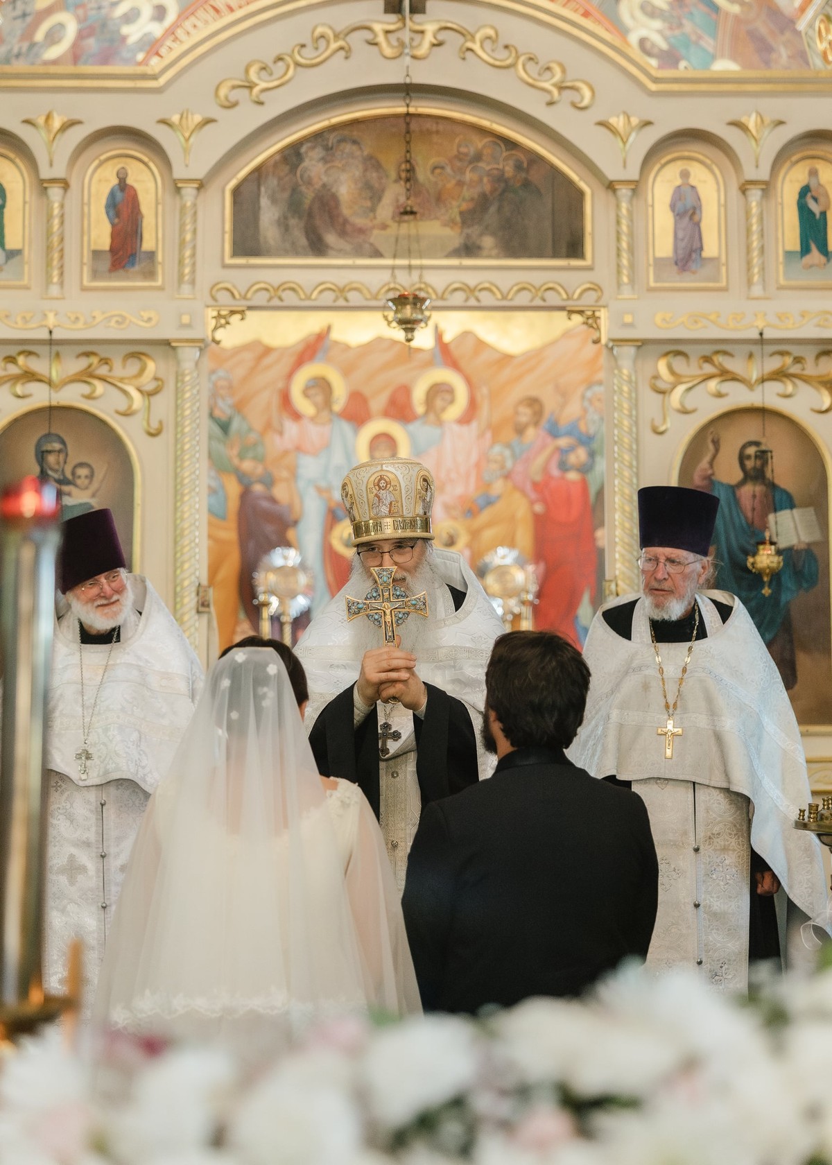 The bride and groom kneel before the bishop