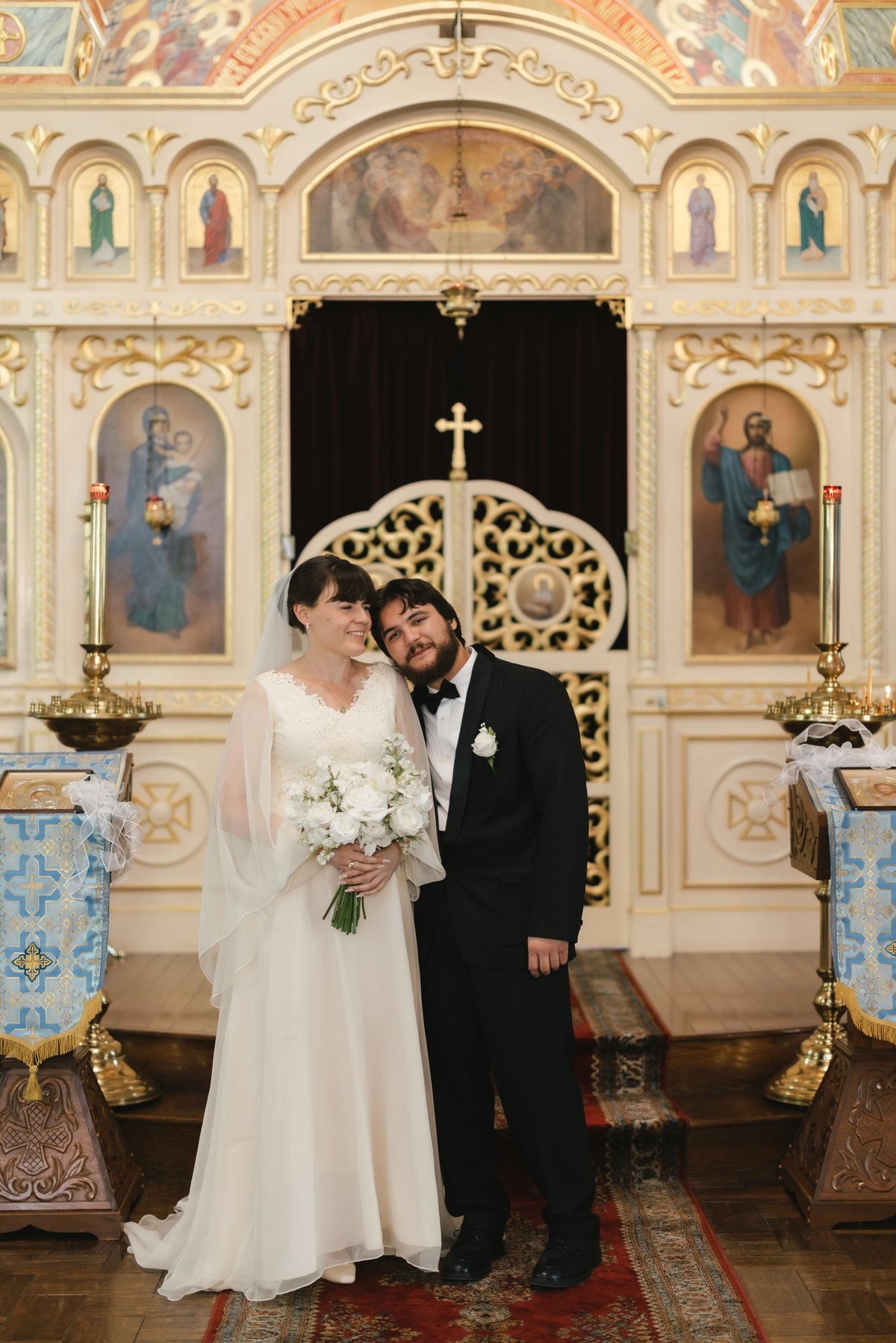 A bride and groom pose in the royal doors of an Orthodox church