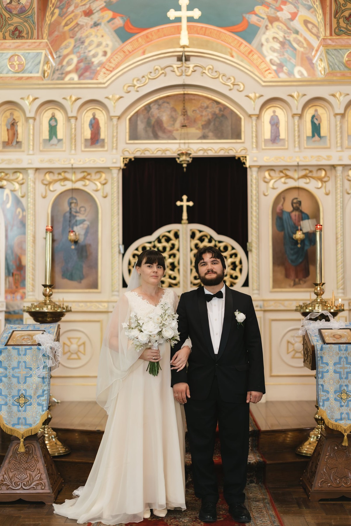 A bride and groom pose in the royal doors of an Orthodox church