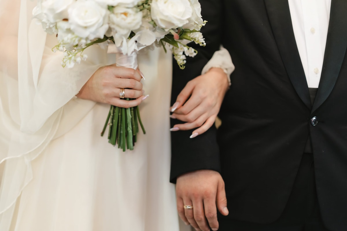 The couple's hands and the bride's white bouquet