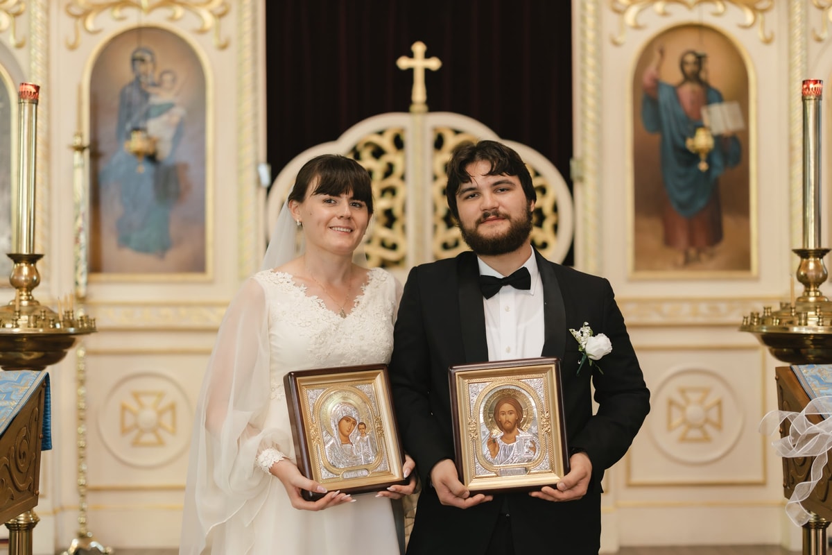The bride and groom hold icons presented after their wedding