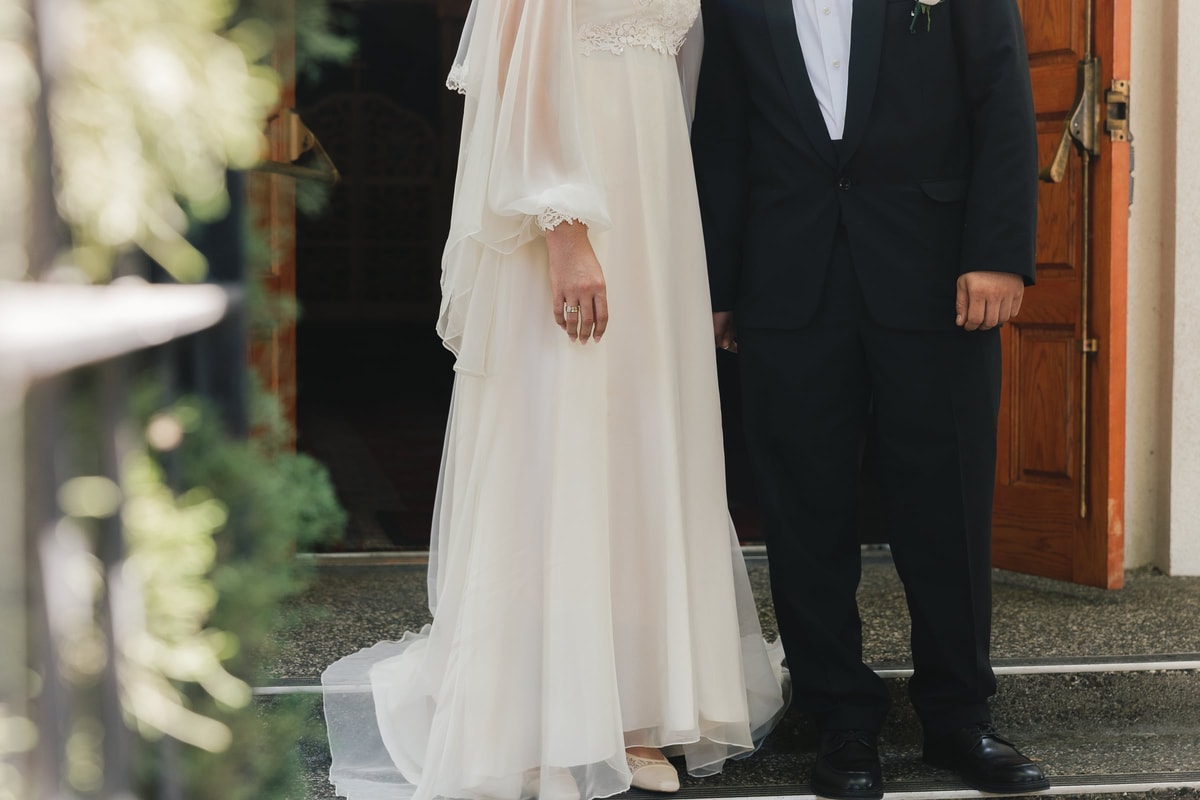 The bride and groom stand together outside the church