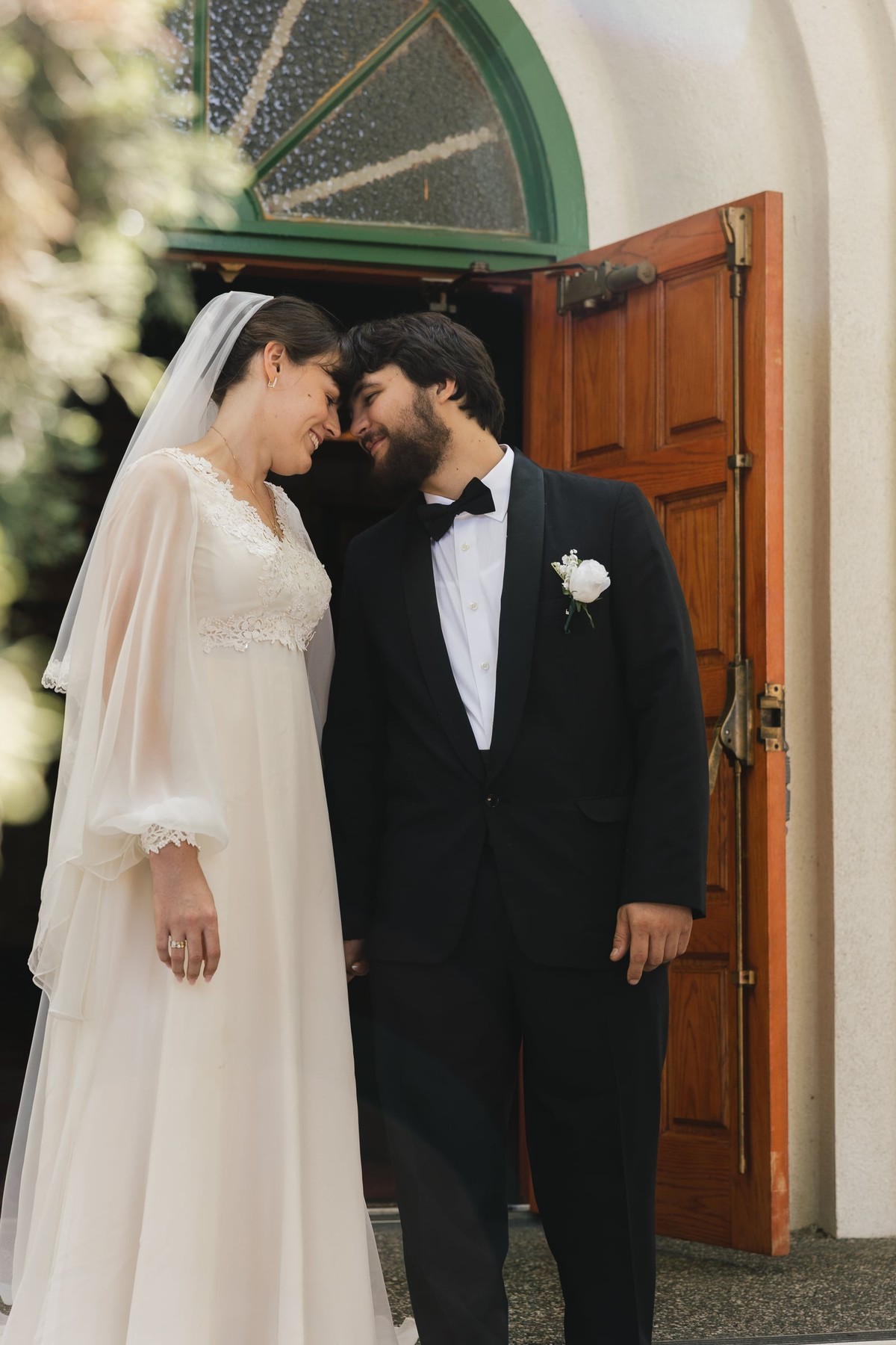 A bride and groom stand together outside an Orthodox church