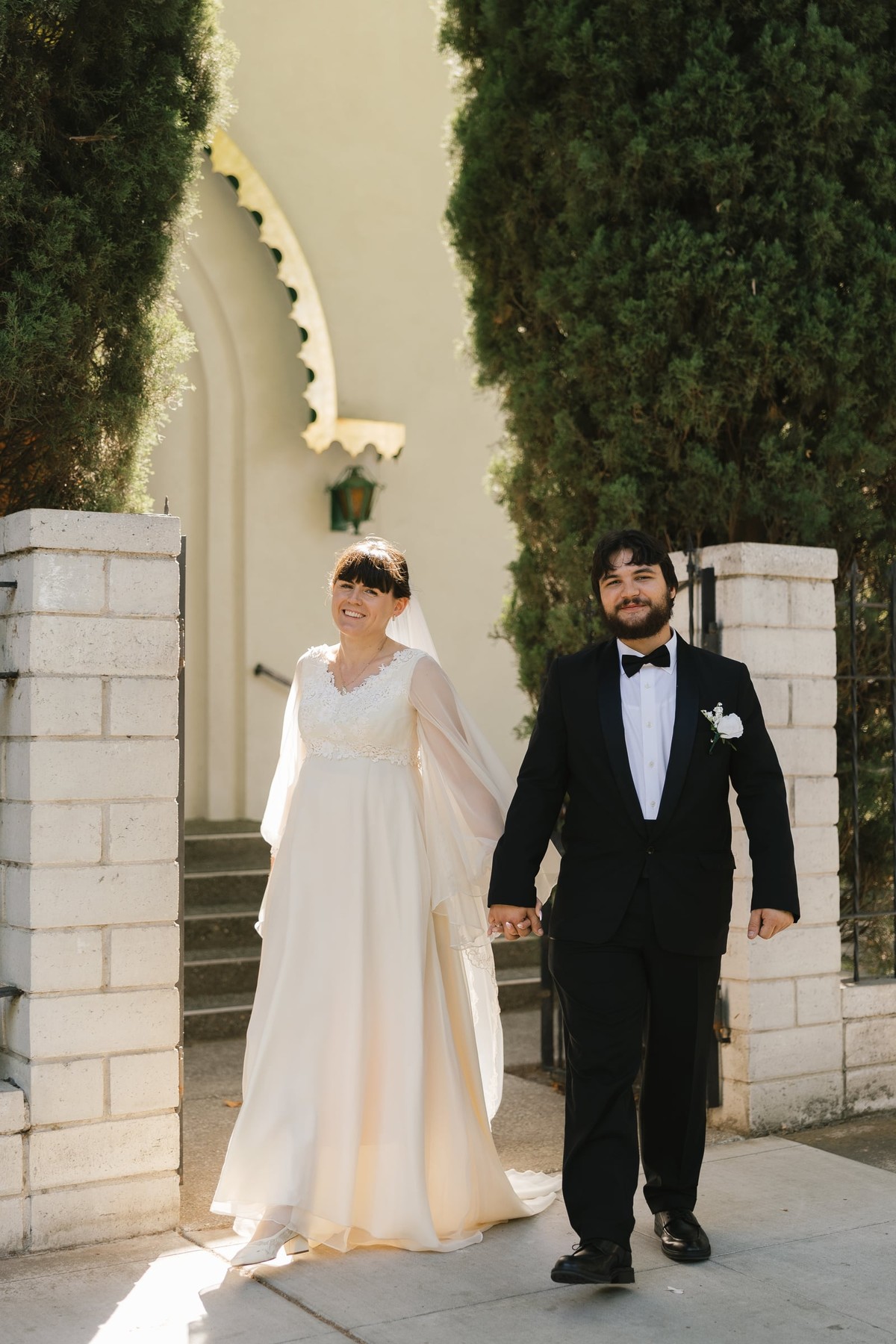 A bride and groom walk together outside an Orthodox church
