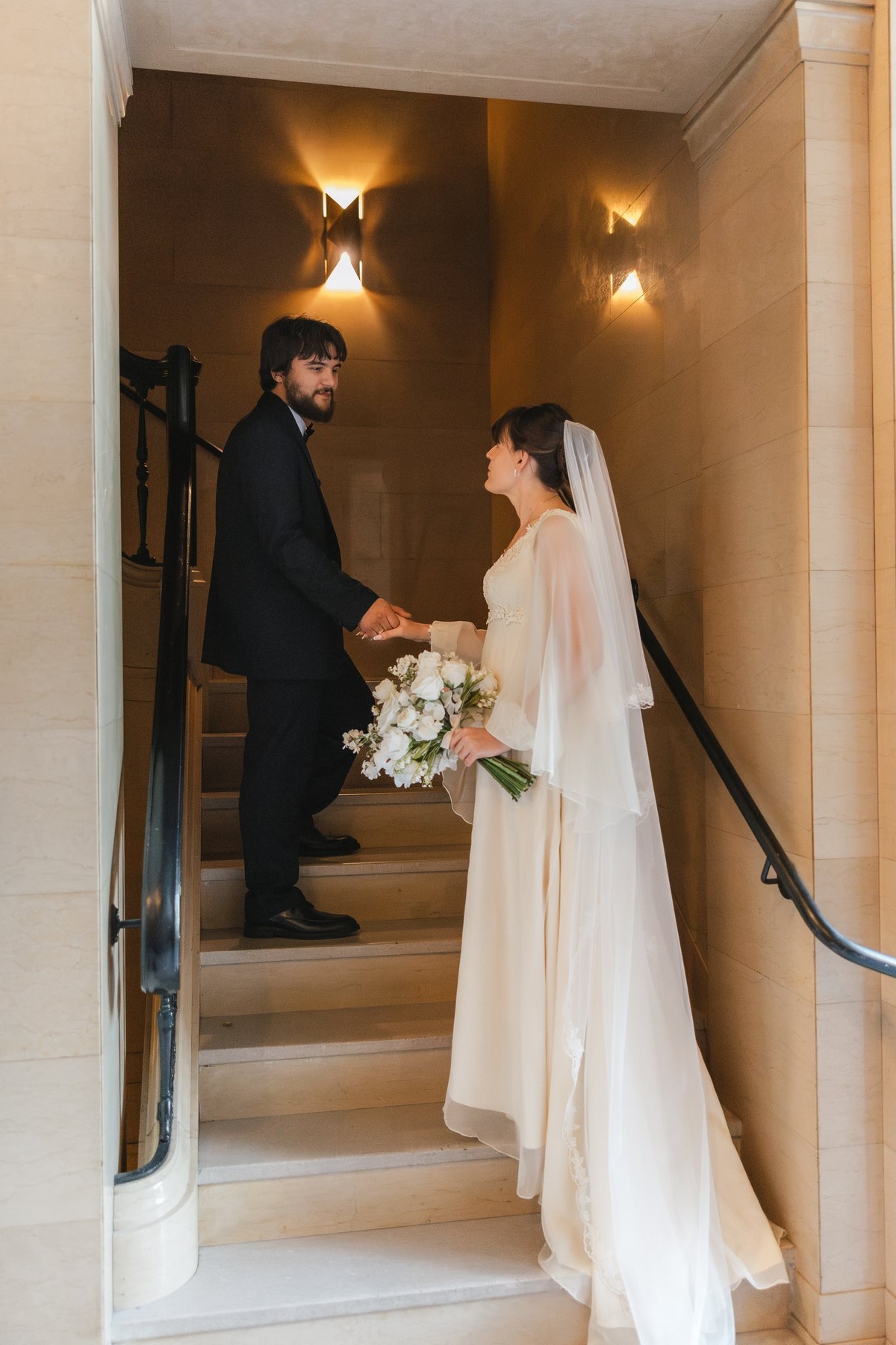 The bride and groom face one another on a stairway