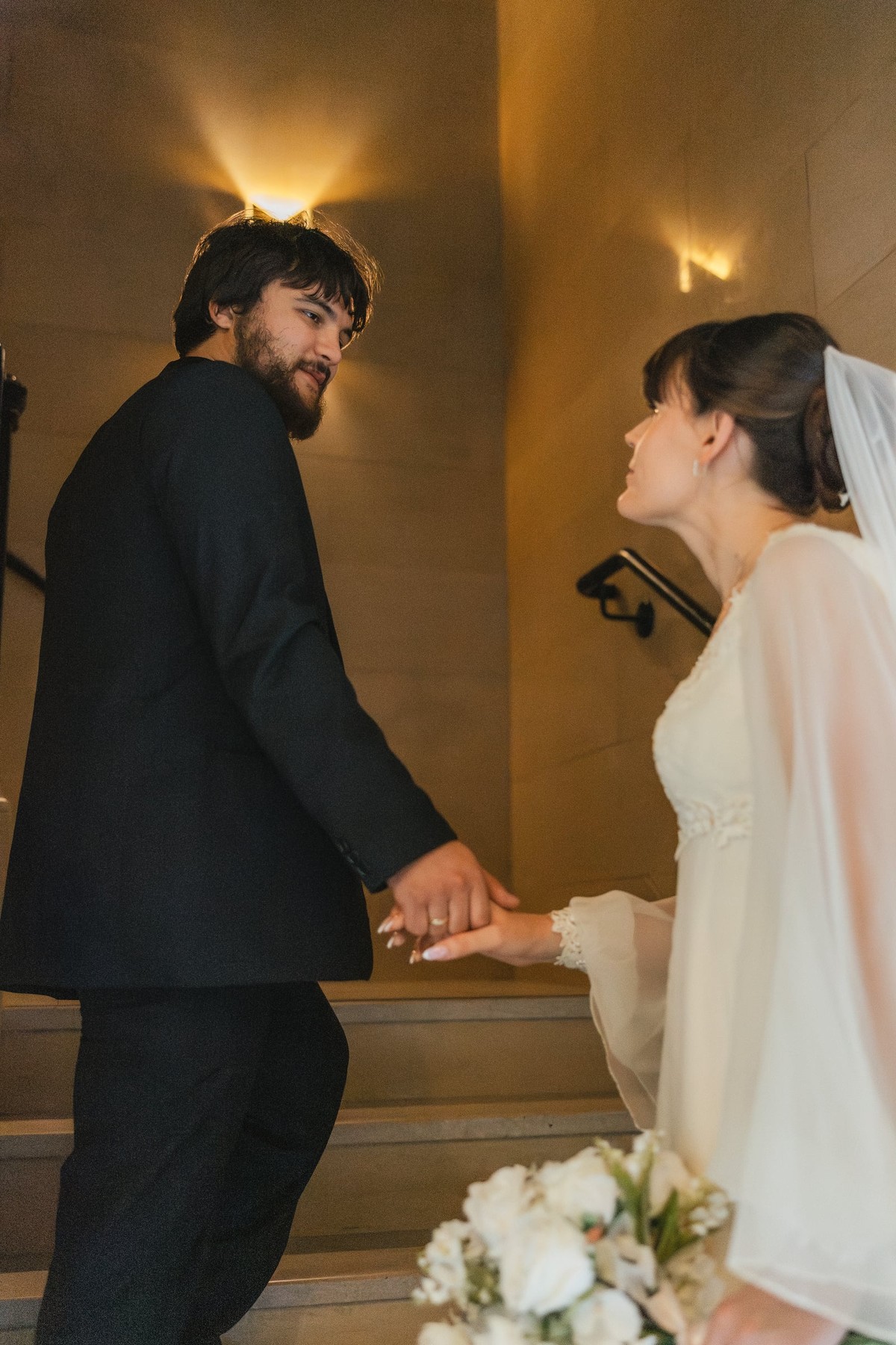 The bride and groom walk upstairs holding hands