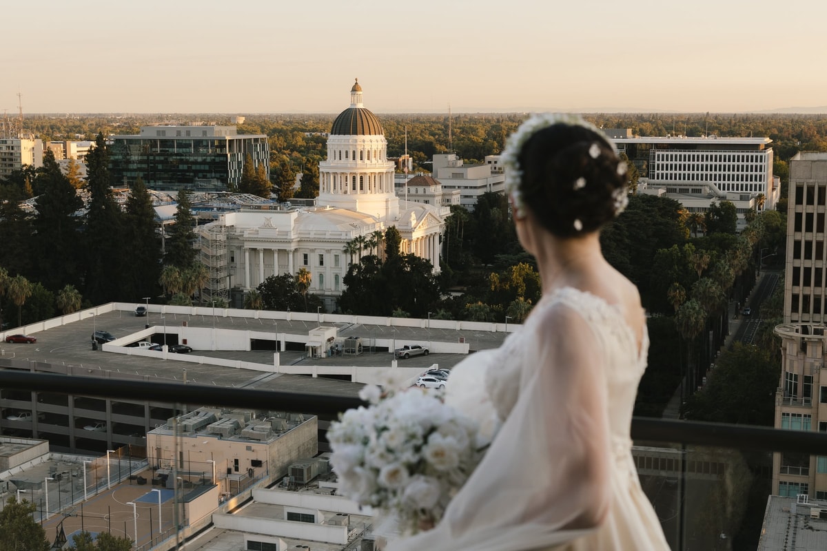 A bride looks across a city from a rooftop terrace