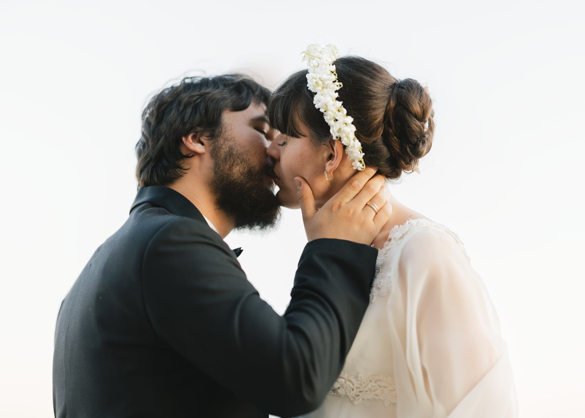 The bride and groom kiss in a bright rooftop portrait