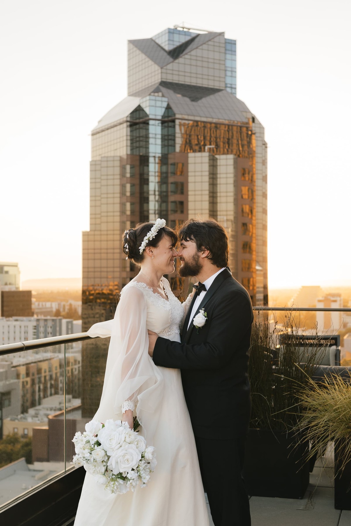 The bride and groom pose together against the city skyline