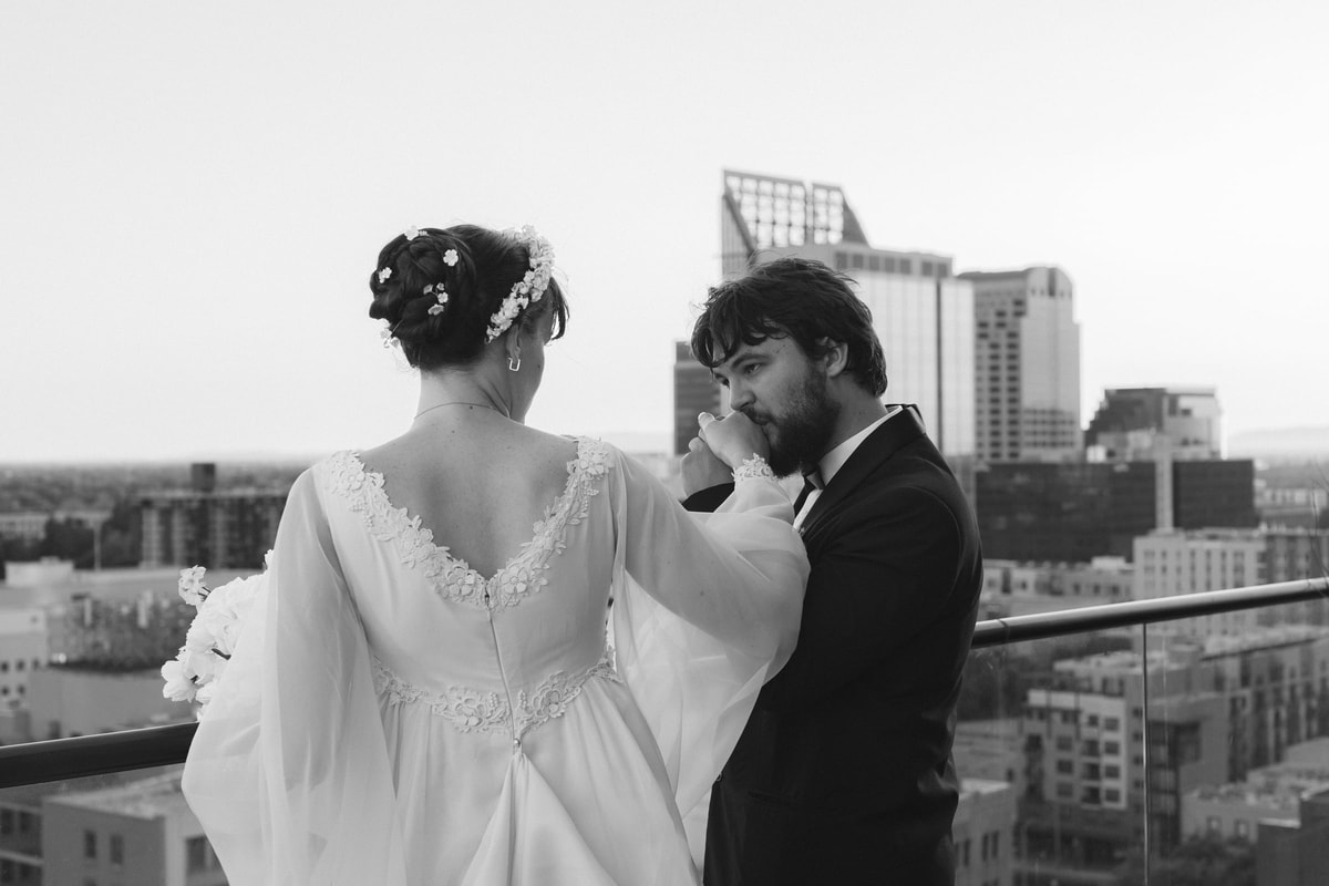 The bride touches the groom's face in a black-and-white rooftop portrait
