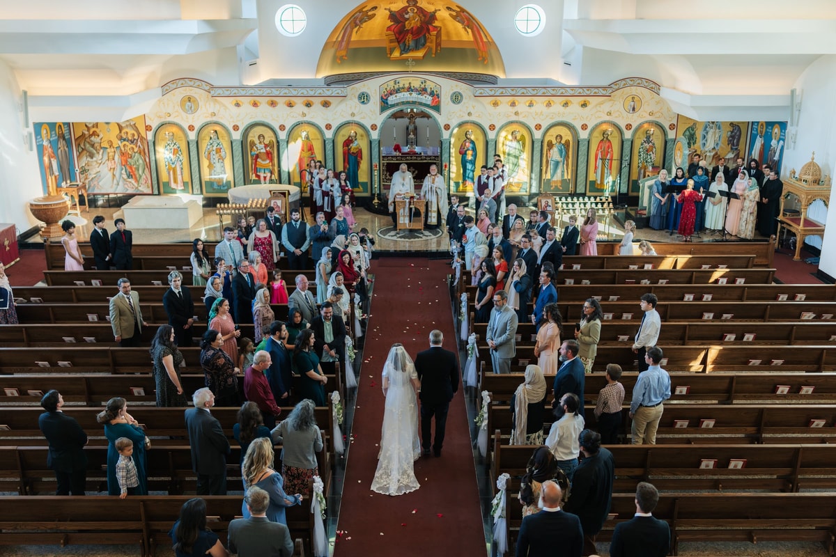 A bride enters an Orthodox church with her escort