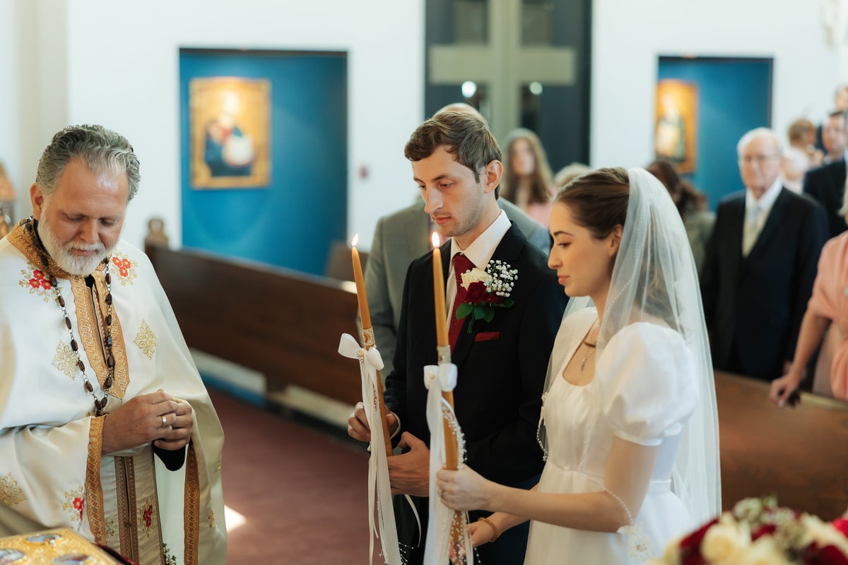 The bride and groom stand before the priest at the start of the ceremony