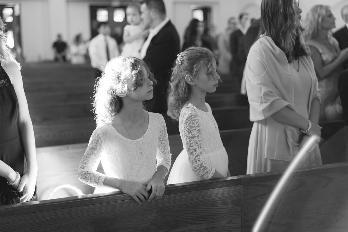 Two children watch from a pew in a black-and-white photograph