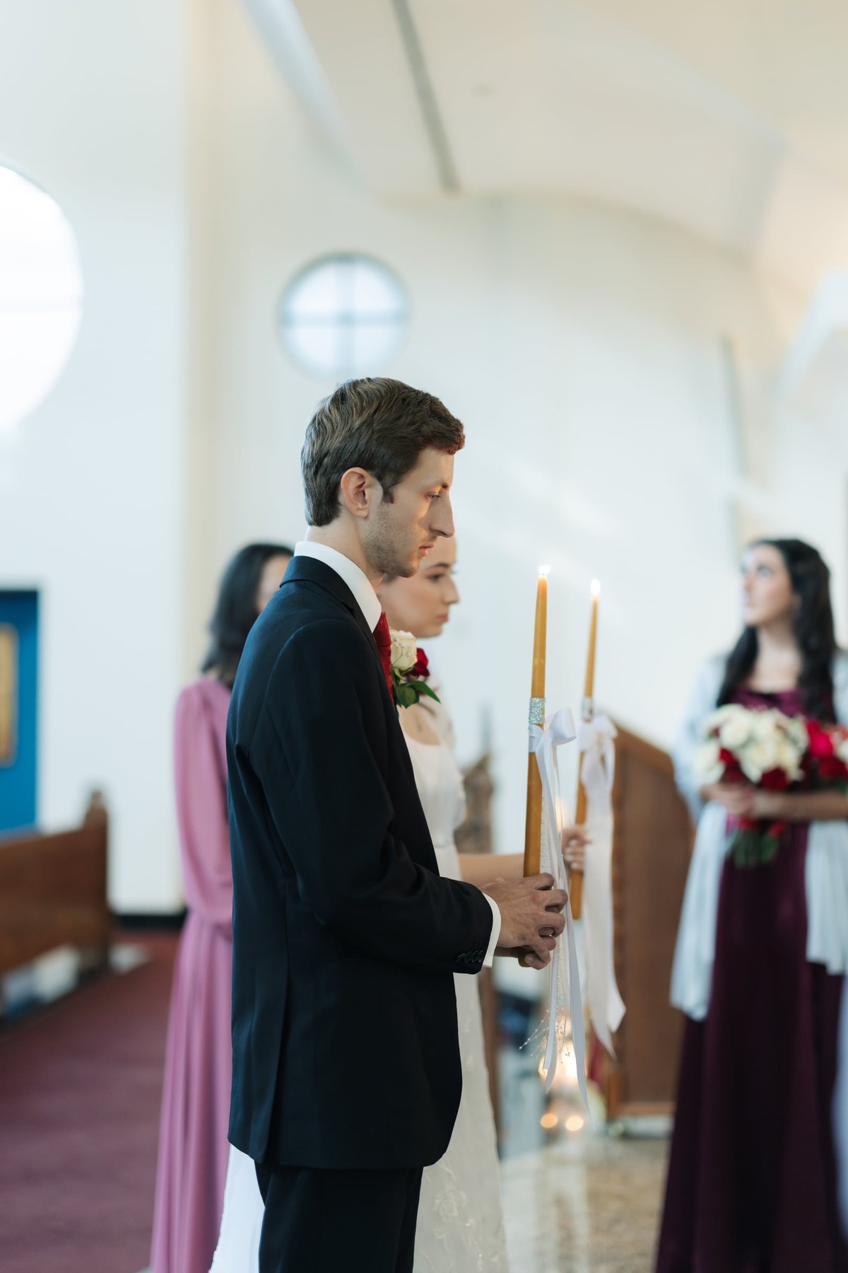 The groom holds two decorated wedding candles