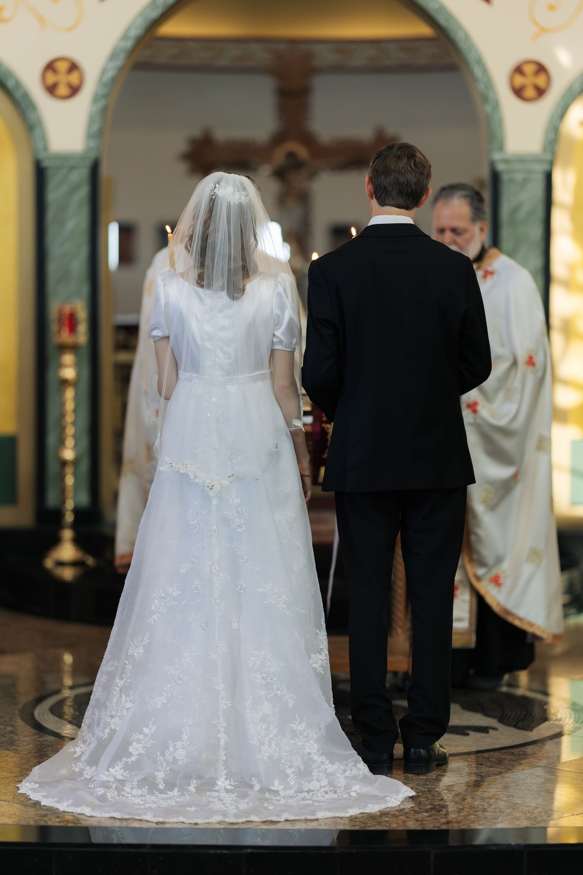 The bride and groom face the iconostasis together