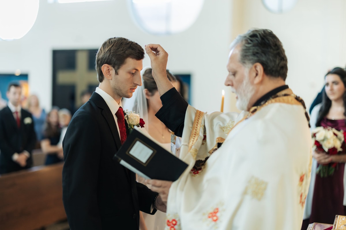 An Orthodox priest blesses the groom during the wedding service