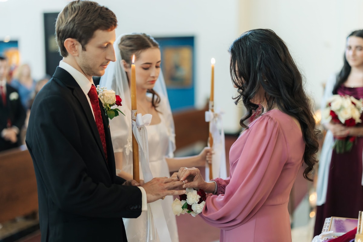 A sponsor exchanges the wedding ring on the groom's hand