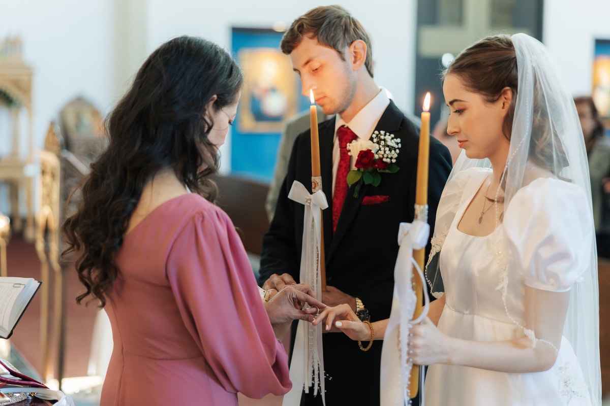 A sponsor exchanges the wedding ring on the bride's hand