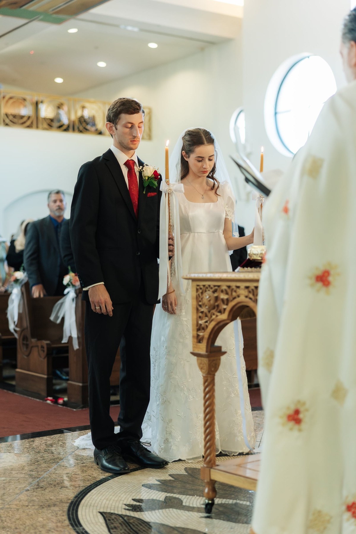 The bride and groom listen to the priest during the marriage prayers