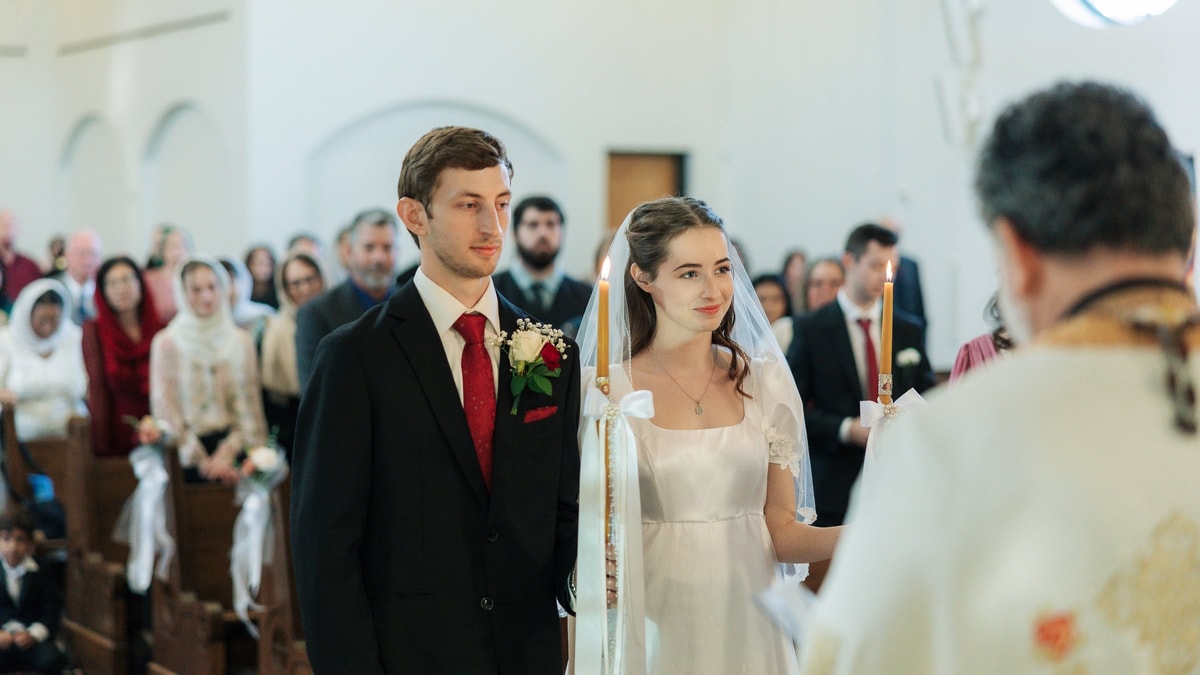 The bride and groom listen to the priest during the marriage prayers