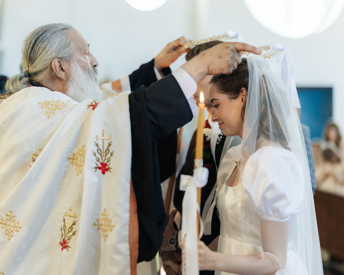 A priest places the bride's wedding crown on her head