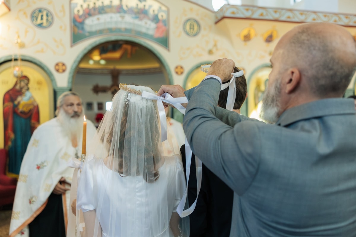 A sponsor exchanges the crowns above the couple