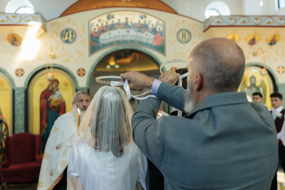 A sponsor exchanges the crowns above the couple