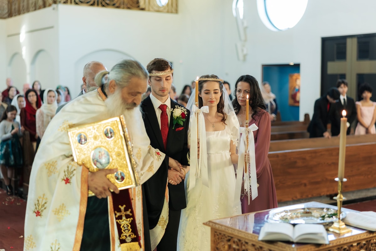 A priest carries the Gospel before the couple