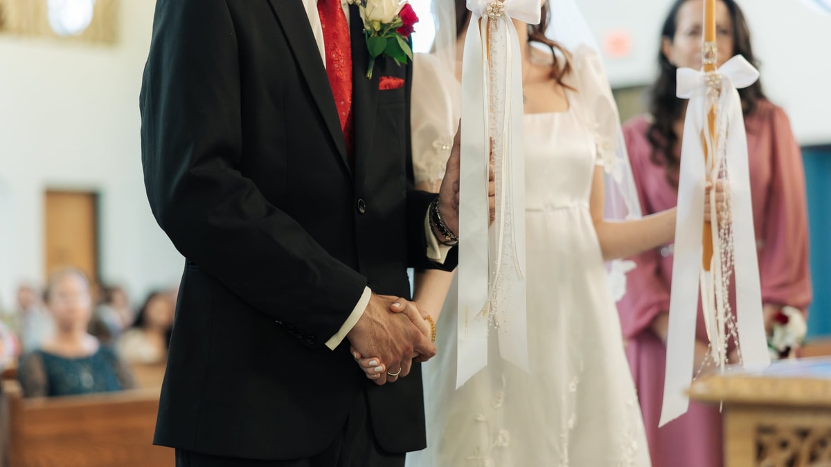 The bride and groom hold hands during the final prayers
