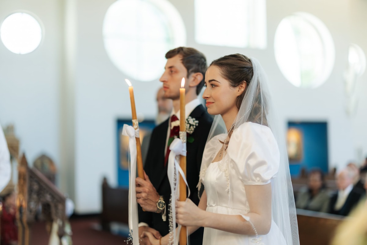The bride and groom hold their wedding candles side by side