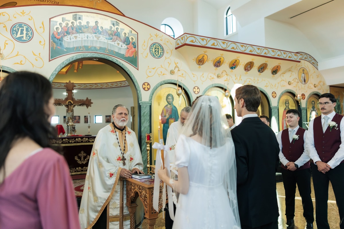 A priest addresses the bride and groom at the end of the ceremony