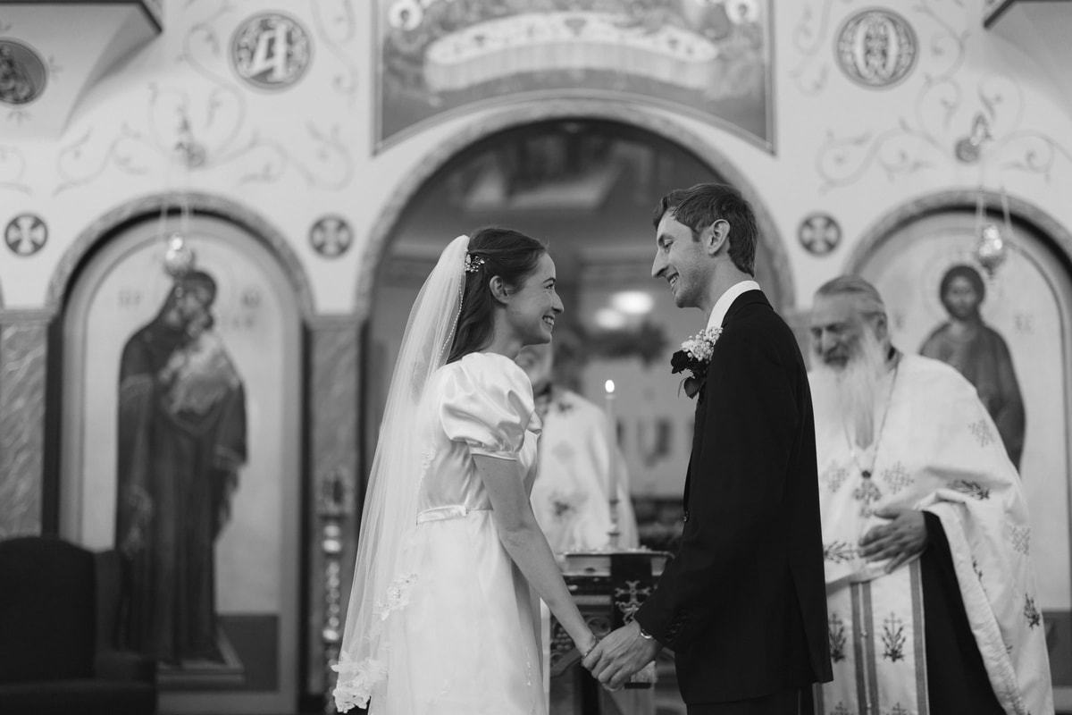 The bride and groom kiss before the iconostasis