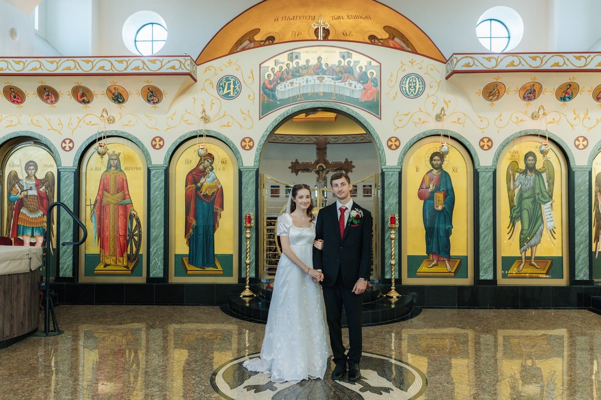 The bride and groom pose together before the iconostasis