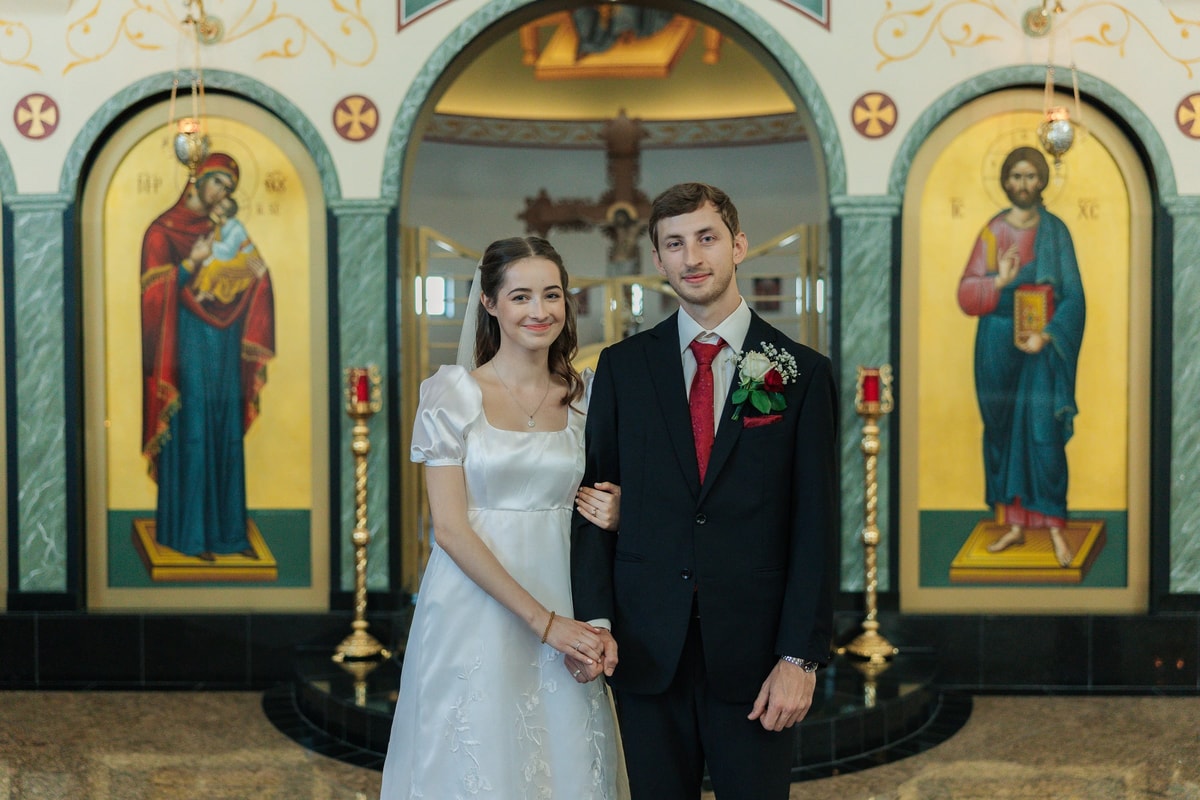The bride and groom stand together for portraits inside the church