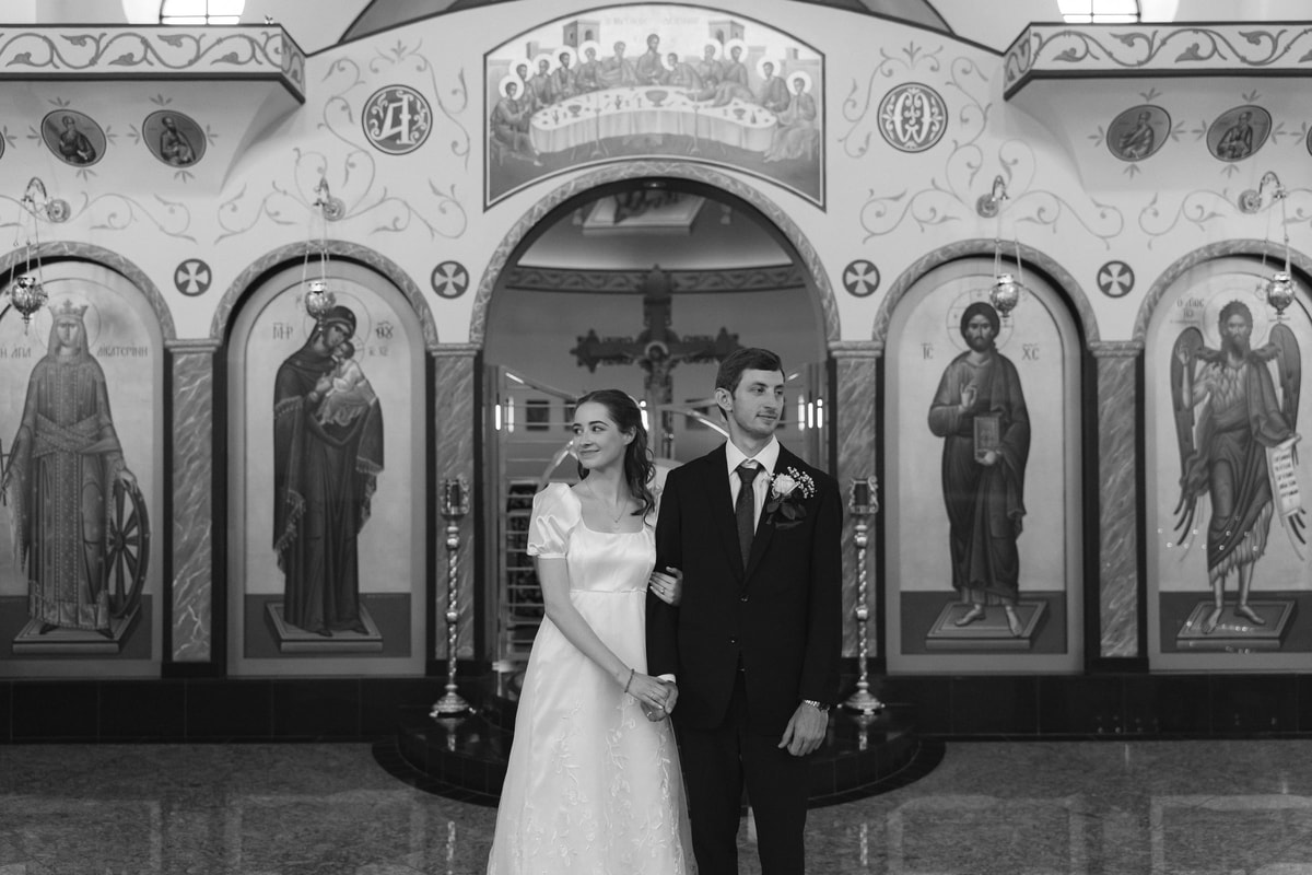The bride and groom stand together for portraits inside the church