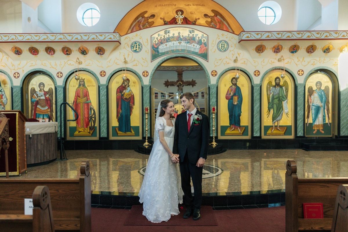 The bride and groom stand together for portraits inside the church