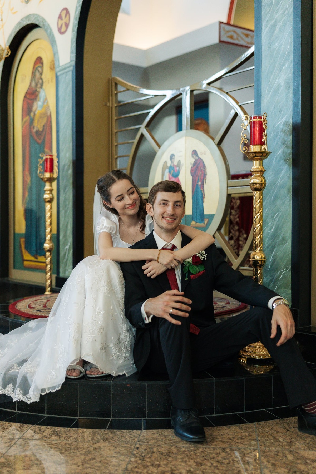 A bride and groom sit together for portraits inside an Orthodox church