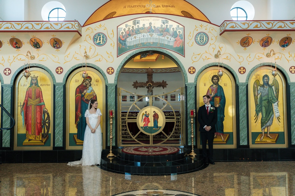 The bride and groom pose on either side of the royal doors