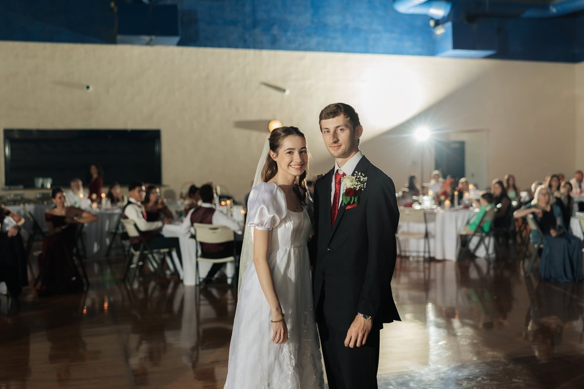 The bride and groom pose together on the reception dance floor