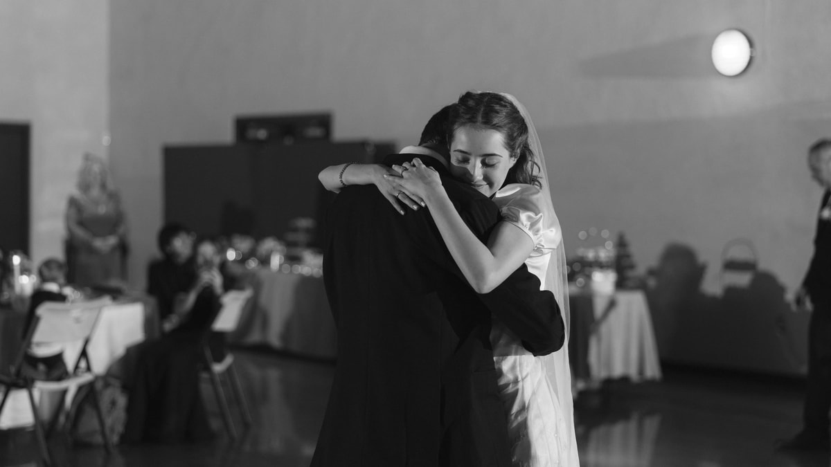 The bride embraces the groom during their first dance in a black-and-white photograph