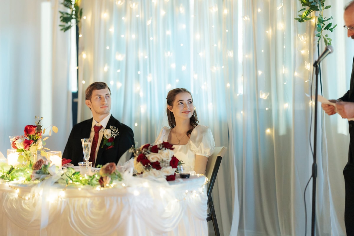 The bride and groom listen to speeches from their reception table