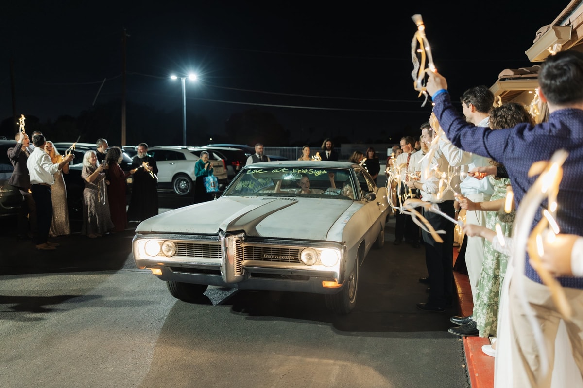 The getaway car leaves through a crowd of wedding guests